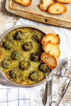 a close up of a casserole dish with bread on the side and text overlay reading homemade escargot recipe