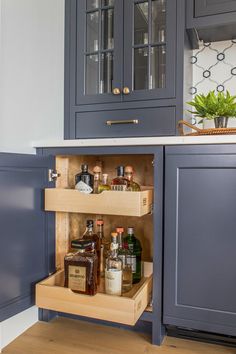 an open cabinet in the middle of a kitchen with liquor bottles and spices on it