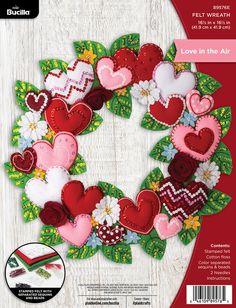 an image of a wreath made out of felt hearts and flowers on a white wooden background