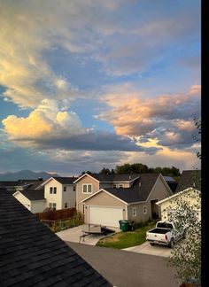 the sky is filled with clouds over houses and cars parked in front of each other