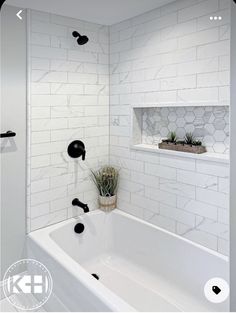 a bathroom with white tile and black fixtures on the walls, along with a bathtub