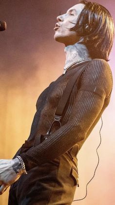 a man with long hair and piercings standing in front of a microphone on stage