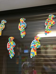 several colorful birds are on the window sill in front of a storefront door