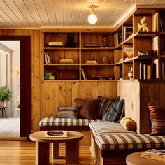 a living room filled with furniture and bookshelves next to a wooden floored wall