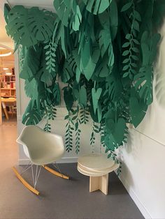 a white rocking chair sitting in front of a wall with green leaves hanging from it