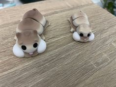 two small toy animals sitting on top of a wooden table next to eachother