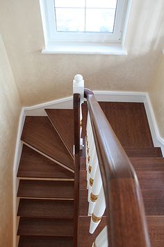 an overhead view of a wooden staircase with white railings and wood handrails