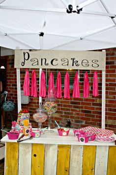 a dessert bar with pink tassels and decorations