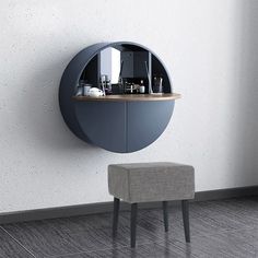 a round mirror mounted to the side of a white wall next to a gray stool