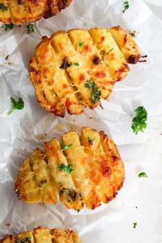 four pieces of food sitting on top of white paper covered in parmesan cheese