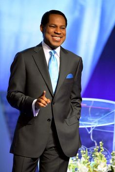 a man in a suit and tie standing next to a table with flowers on it