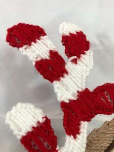 two red and white knitted mittens sitting on top of a piece of wood