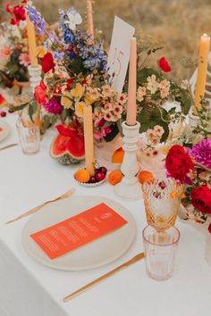 the table is set with flowers, candles and place cards for guests to sit at