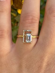 a woman's hand with a ring on it and an emerald stone in the middle