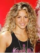 a woman with long curly hair wearing a black tank top and smiling at the camera