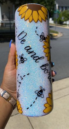 a person holding up a painted water bottle with bees on it and sunflowers