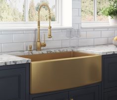 a kitchen with marble counter tops and gold sink faucet in front of the window