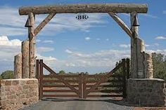 a wooden gate that has the initials hh on it and is surrounded by stone pillars