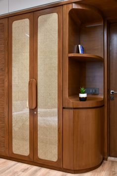 a wooden cabinet with glass doors and a plant in the corner on top of it