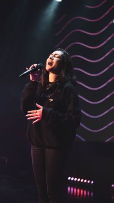 a woman standing on top of a stage holding a microphone in front of her face