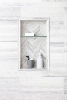 a bathroom with white marble walls and flooring, toiletries and soap dispenser