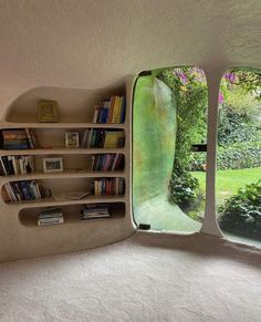 an unusual book shelf is shown in the corner of a room with two windows that look out onto a garden