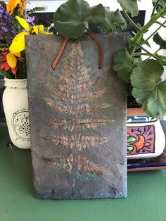 a plant in a pot next to a paper bag on a table with other flowers