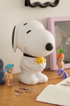 a snoopy figurine sitting on top of a desk next to other toys