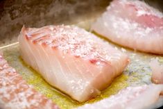 two pieces of fish sitting on top of a frying pan covered in oil and salt