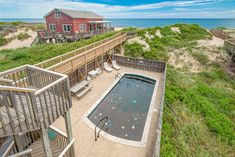 an empty swimming pool in the middle of some sand dunes and beach houses on the other side