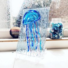 a glass jellyfish is sitting on a window sill