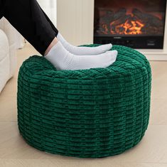 a person sitting on a bean bag chair in front of a fireplace with their feet propped up