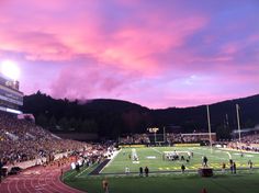 a stadium filled with lots of people watching a football game at sunset or dawn in the evening