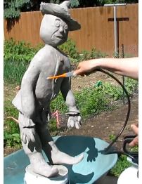 a statue is being worked on by someone in the yard with a garden hose attached to it