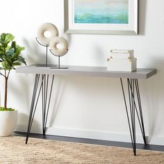 a modern console table with hairpin legs in front of a painting on the wall