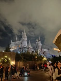 people are standing in front of hogwart's castle at night with lights on