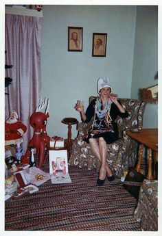 a woman sitting on a couch in a living room next to a christmas tree and other decorations