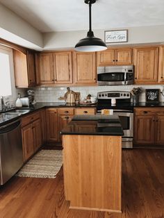 a kitchen with wooden cabinets and stainless steel appliances, including an island in the middle