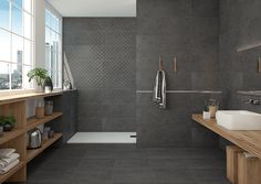 a bathroom with gray tile and wooden shelves