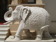 an elephant statue sitting on top of a stone step next to a wall and steps