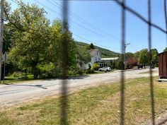 the view from behind a wire fence looking at a small town with houses in the background