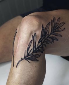 a tattoo on the leg of a person with an olive branch and leaves in it