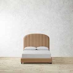 a bed sitting on top of a wooden floor next to a white wall