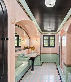 this bathroom has pink and green tile on the walls, along with black trimming