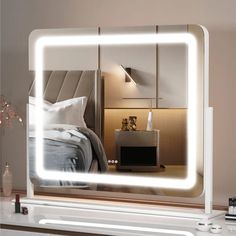 a bedroom with a large lighted mirror on the wall next to a night stand and nightstand