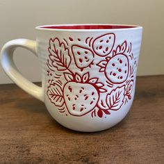 a red and white coffee cup sitting on top of a wooden table