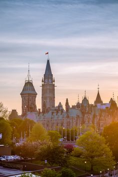 an old building with towers and spires in front of the sun setting behind it