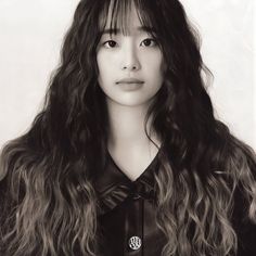 a black and white photo of a young woman with long wavy hair wearing a shirt