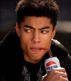 a close up of a person holding a can of pepsi with a straw in his mouth