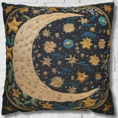 a decorative pillow with an image of the moon and stars on it, against a white brick wall